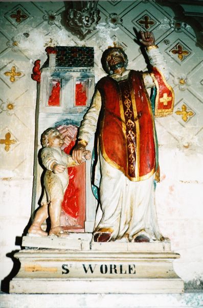 Sint Vorles, gekleed in kazuifel - hij komr immers recht uit de mis! - redt een kind uit een brandend huis. Hij wijst op de hemel waaraan het kind zijn leven te danken heeft, en Sint Vorles de bewondering bij de mensen.